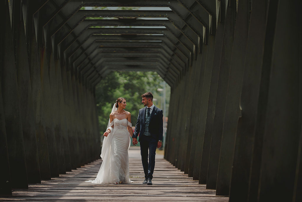 Pareja de novios paseando por un puente de metal